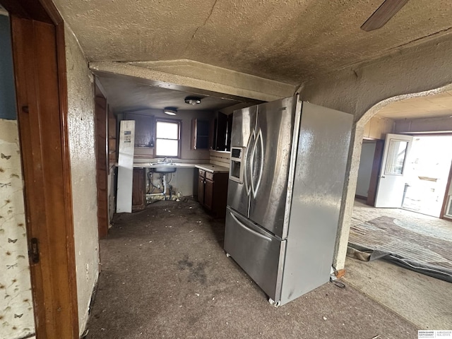 kitchen with light countertops, arched walkways, and stainless steel refrigerator with ice dispenser