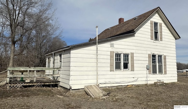 view of side of home with a chimney and a deck