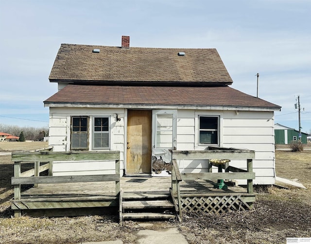 rear view of house featuring a chimney and a wooden deck