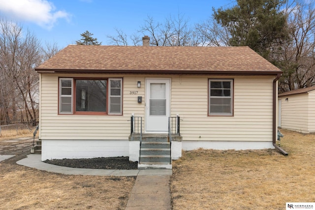 bungalow featuring a front yard and roof with shingles