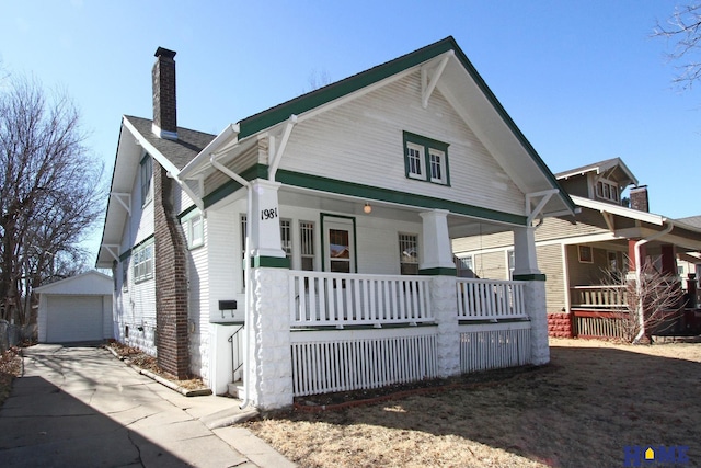 view of front of home with an outbuilding, driveway, a porch, a garage, and a chimney