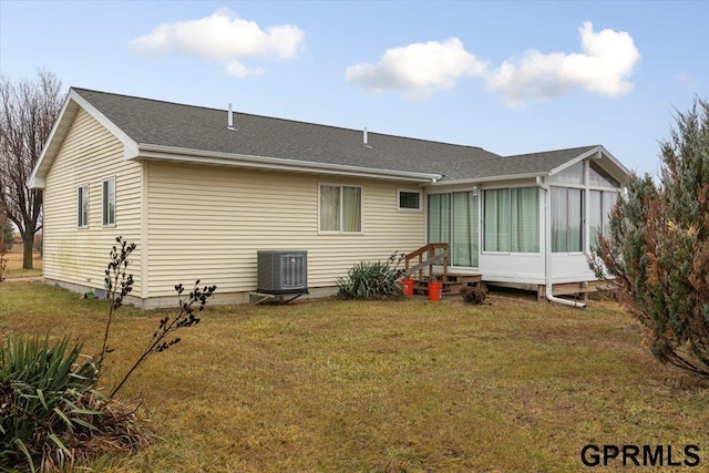 rear view of property with cooling unit, a yard, and a sunroom