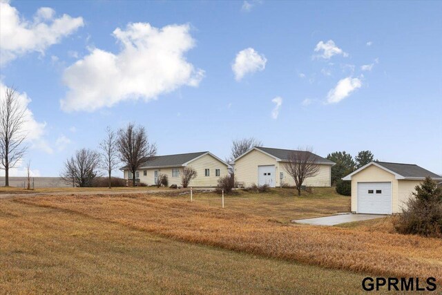 view of front of house with a detached garage, an outdoor structure, and a front lawn