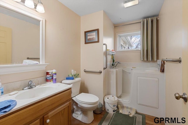 full bathroom featuring toilet, vanity, and a garden tub