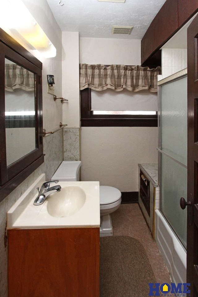 bathroom featuring visible vents, toilet, vanity, enclosed tub / shower combo, and a textured ceiling