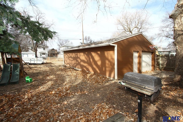 view of outbuilding with an outdoor structure, a playground, and fence