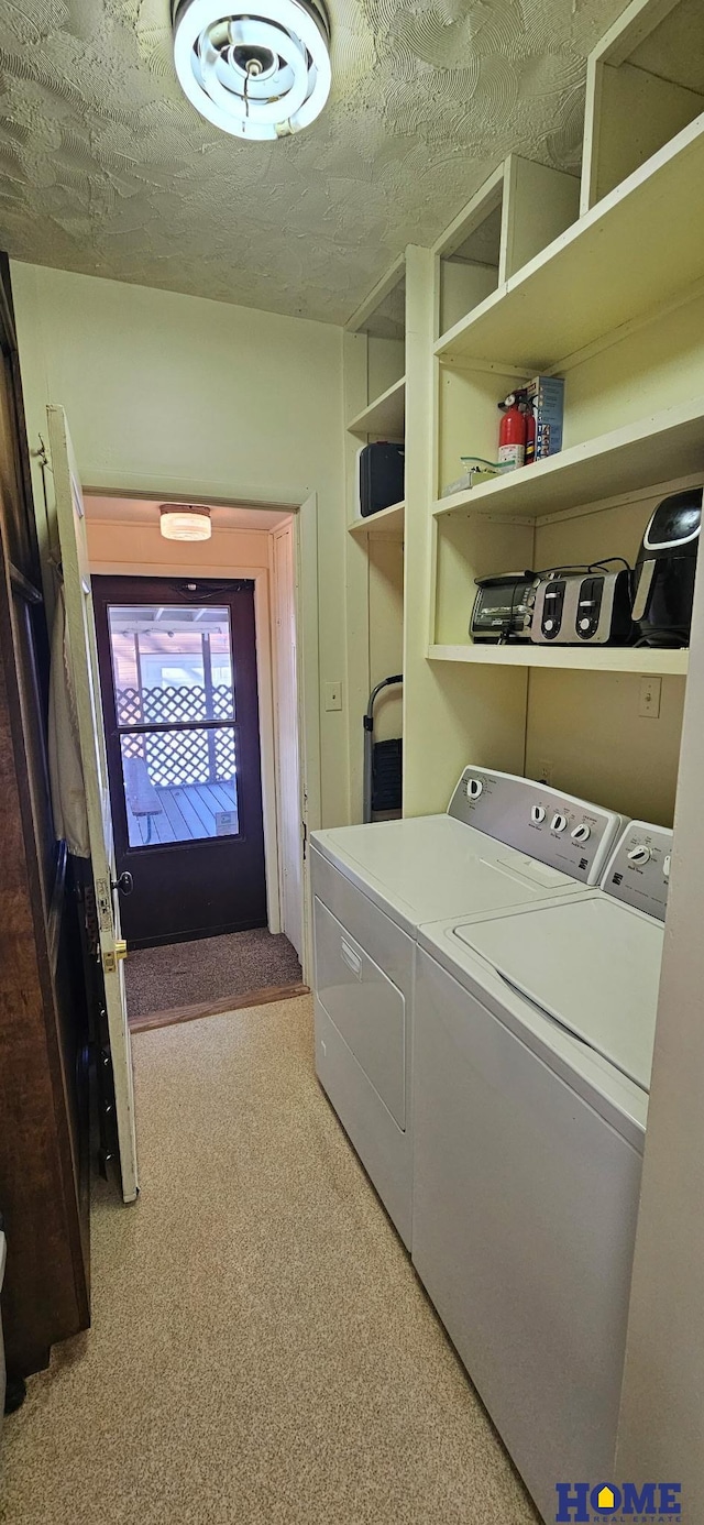 clothes washing area featuring laundry area, washing machine and dryer, and a textured ceiling