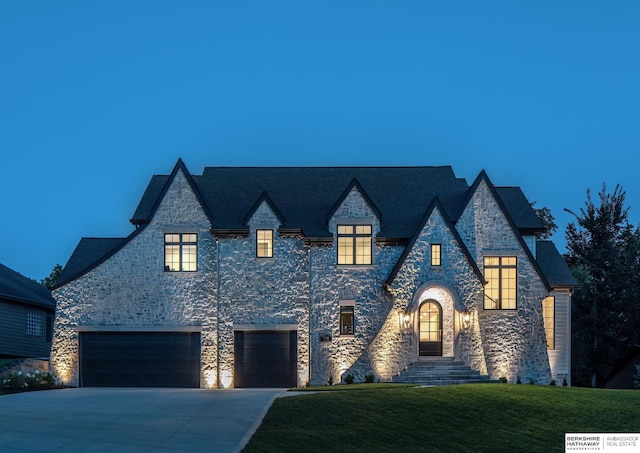 french country style house featuring a front yard, a garage, and driveway