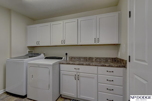 clothes washing area featuring washing machine and clothes dryer, cabinet space, and a textured ceiling