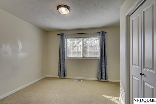 unfurnished room featuring visible vents, a textured ceiling, baseboards, and carpet floors