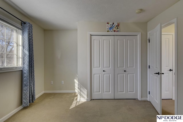 unfurnished bedroom with a closet, baseboards, carpet floors, and a textured ceiling