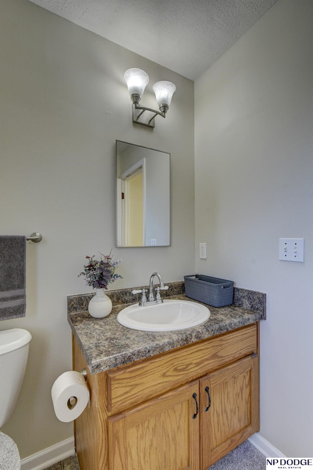 bathroom with baseboards, a textured ceiling, and vanity