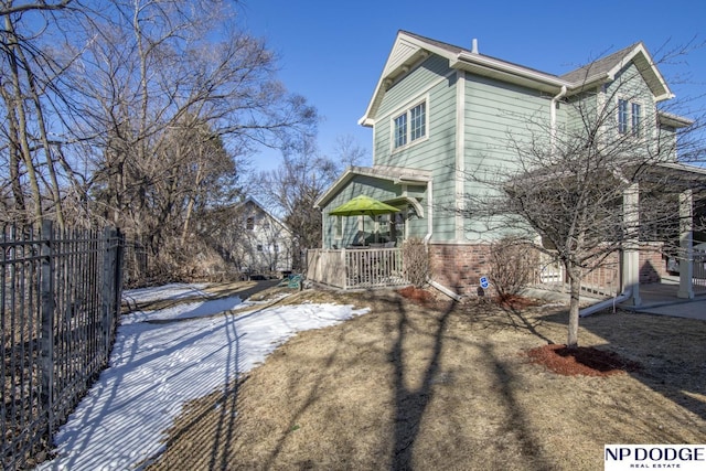 view of snowy exterior with fence and brick siding