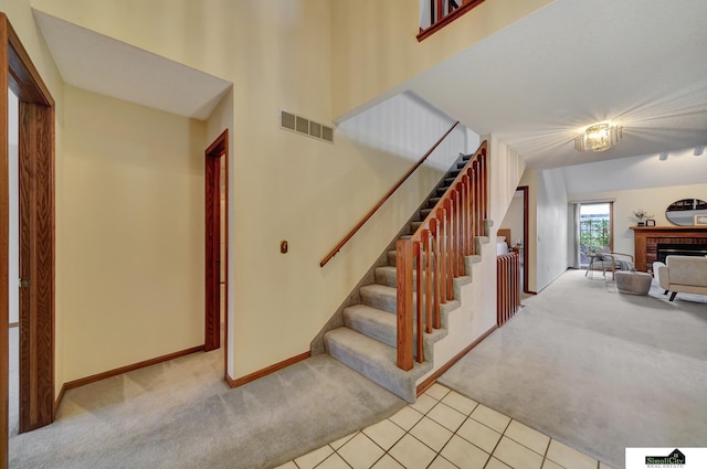 stairs with a fireplace, carpet, visible vents, and baseboards