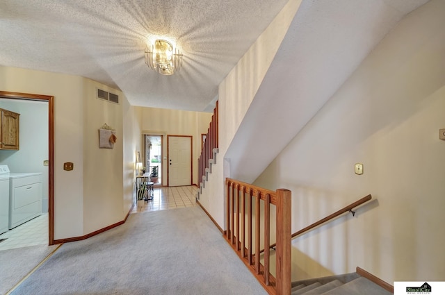 corridor featuring visible vents, stairs, light carpet, washer and dryer, and a textured ceiling