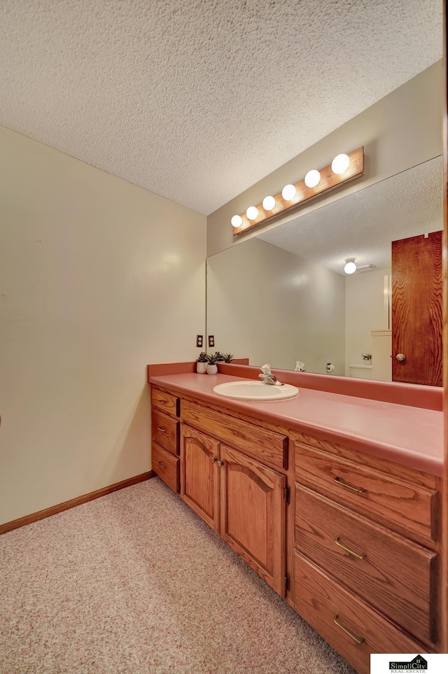 bathroom featuring a textured ceiling, vanity, and baseboards