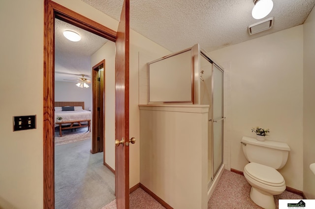 ensuite bathroom with baseboards, visible vents, a shower stall, a textured ceiling, and toilet