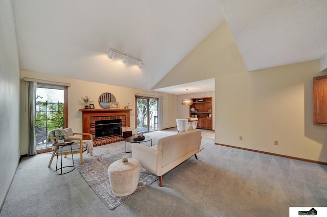 living room with baseboards, light carpet, a fireplace, rail lighting, and high vaulted ceiling