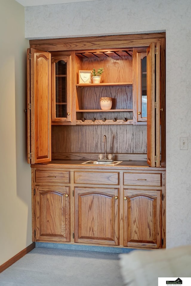 bar with wet bar, baseboards, and a sink