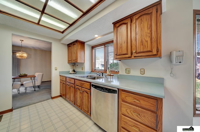 kitchen with a sink, dishwasher, brown cabinetry, and light countertops