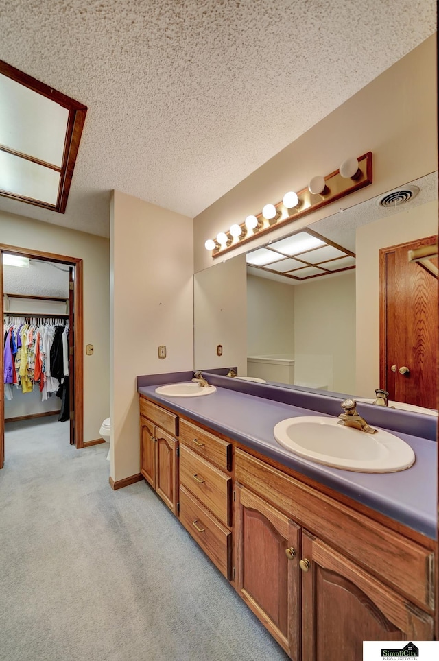 full bathroom featuring a sink, baseboards, a textured ceiling, and double vanity