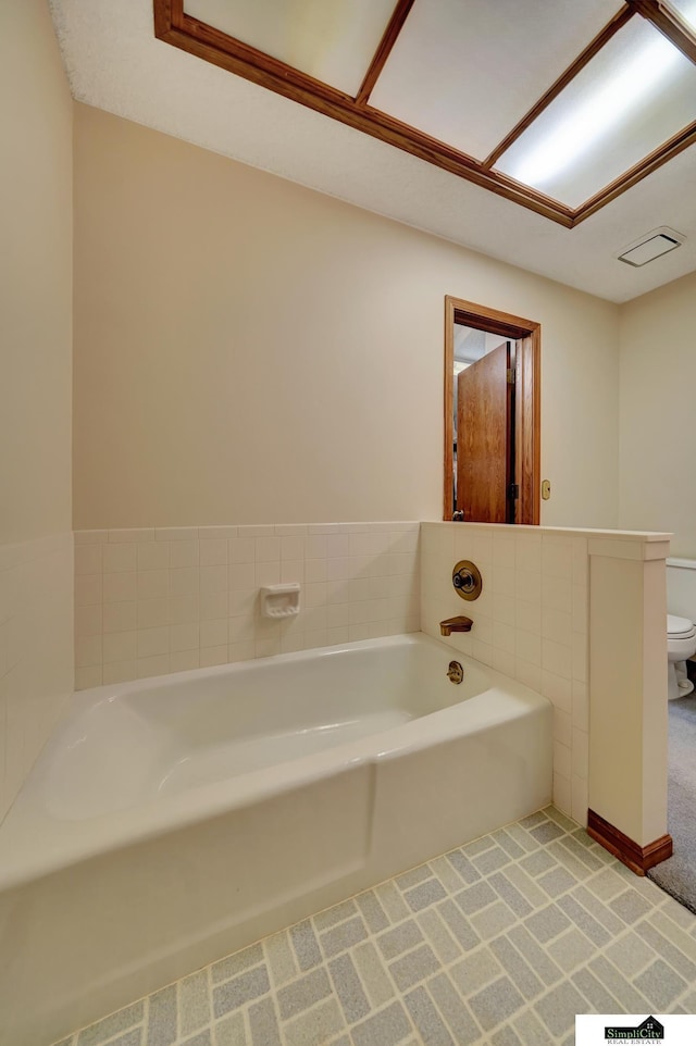 full bathroom featuring a garden tub and toilet