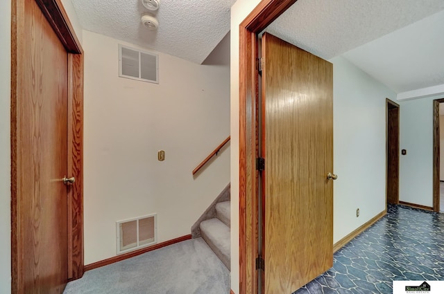 staircase featuring visible vents, baseboards, and a textured ceiling