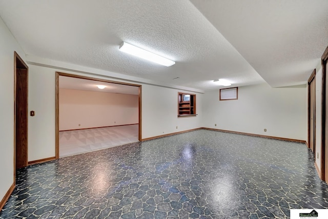 finished basement with a textured ceiling and baseboards