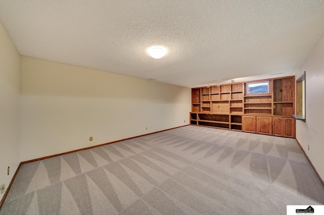 interior space featuring baseboards, light carpet, and a textured ceiling