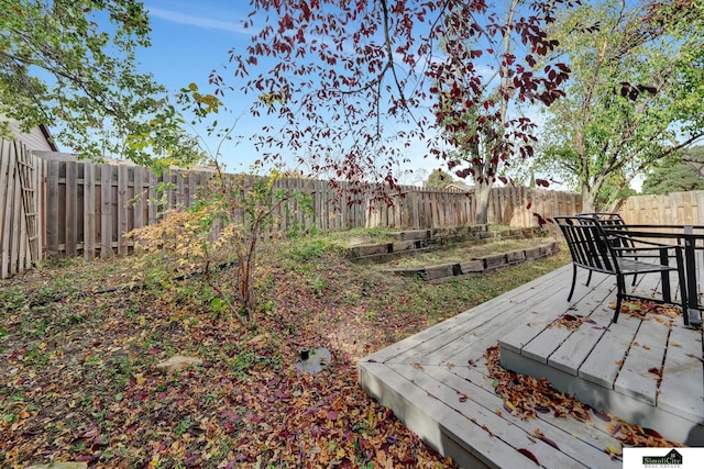 view of yard featuring a vegetable garden, a wooden deck, and a fenced backyard