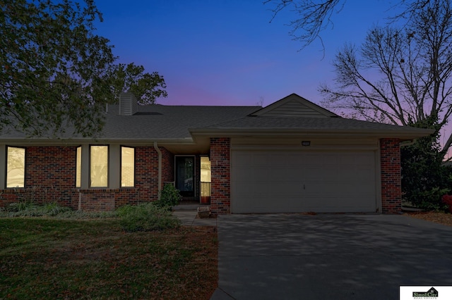 single story home featuring brick siding, an attached garage, a shingled roof, a chimney, and driveway