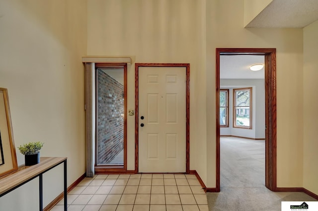 foyer featuring light tile patterned flooring, visible vents, light colored carpet, and baseboards