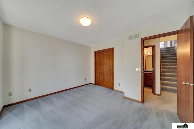 unfurnished bedroom with baseboards, visible vents, carpet floors, a closet, and a textured ceiling