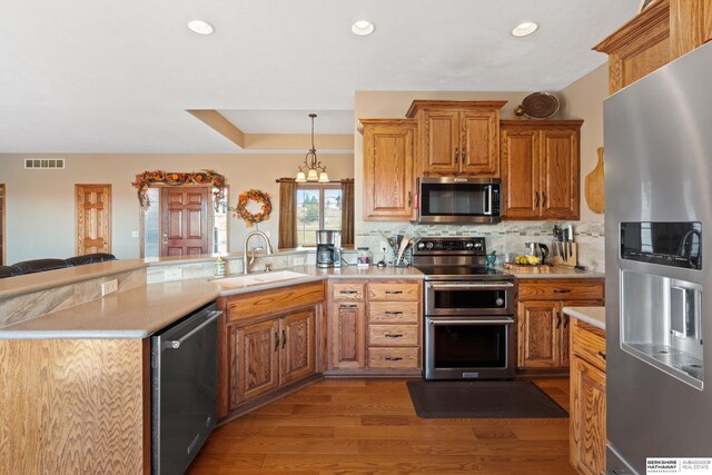 kitchen with visible vents, a peninsula, a sink, stainless steel appliances, and light countertops