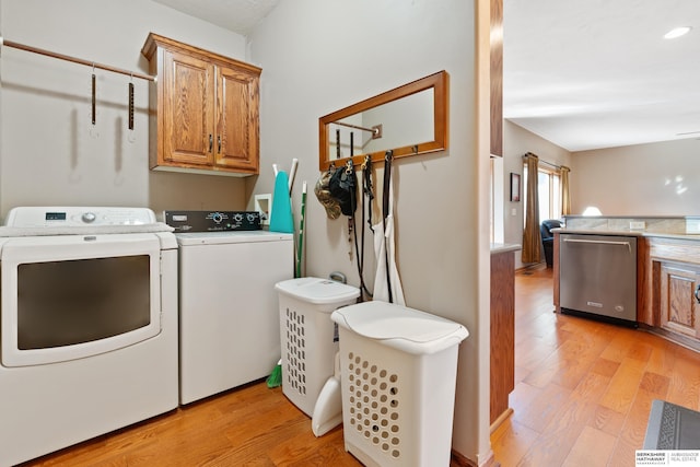 laundry room with separate washer and dryer, cabinet space, and light wood-style floors