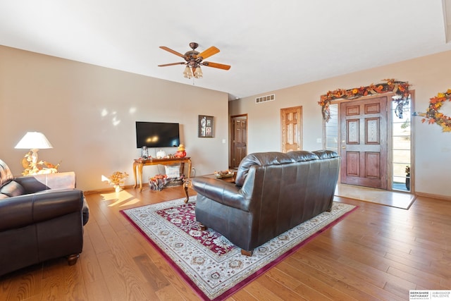 living room with light wood-type flooring, visible vents, baseboards, and ceiling fan