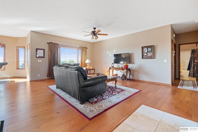 living room with baseboards, light wood-type flooring, and ceiling fan