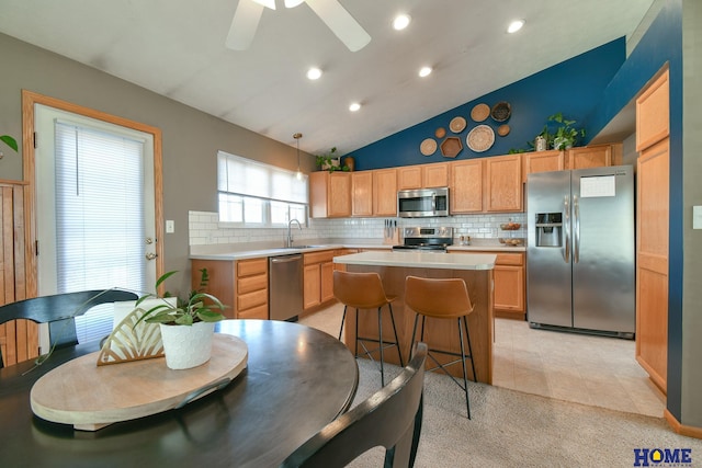 kitchen featuring a sink, a center island, stainless steel appliances, light countertops, and decorative backsplash