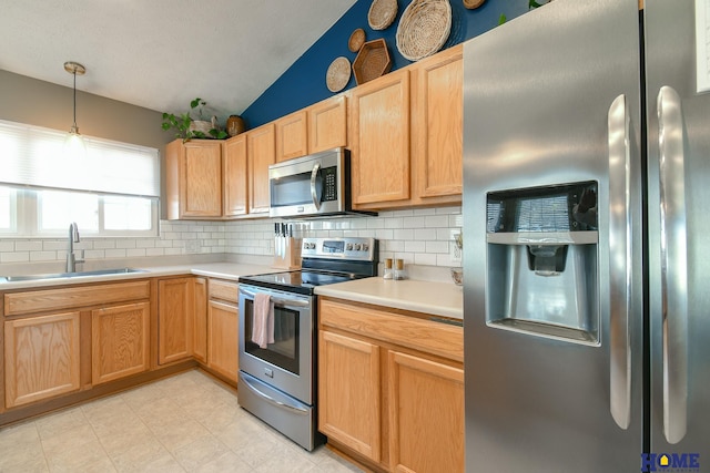 kitchen with lofted ceiling, a sink, light countertops, appliances with stainless steel finishes, and backsplash