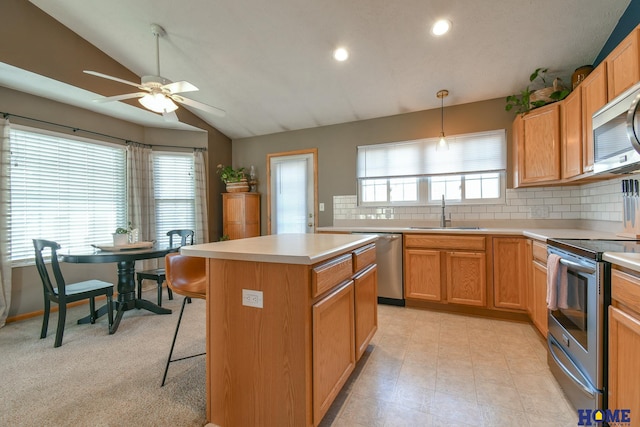 kitchen with ceiling fan, light countertops, vaulted ceiling, appliances with stainless steel finishes, and a sink