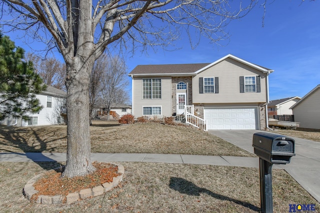 raised ranch featuring concrete driveway and an attached garage