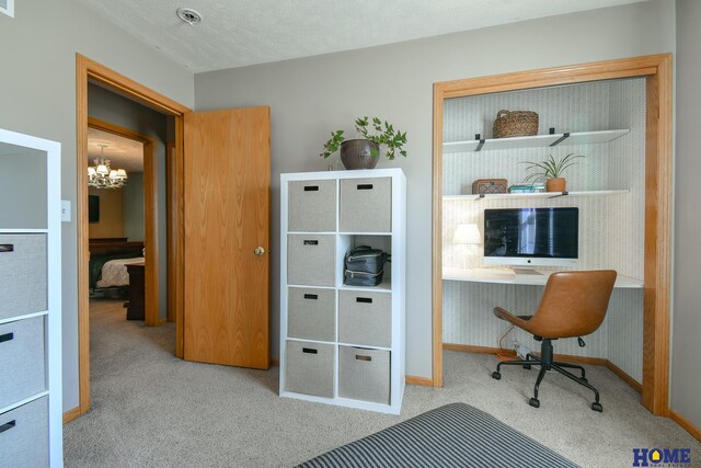 carpeted office space featuring a chandelier, a textured ceiling, and baseboards