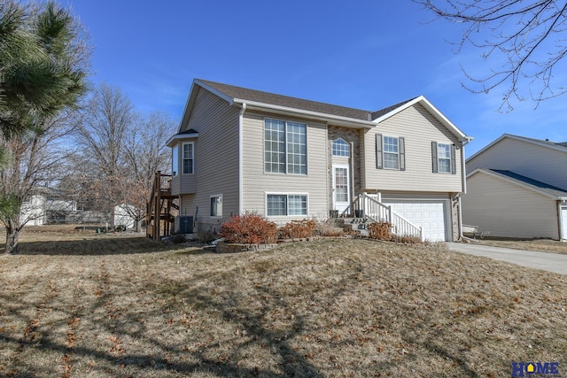 raised ranch with central AC unit, concrete driveway, stairs, and a garage