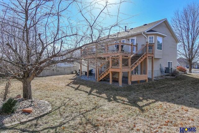 rear view of property with fence, a yard, a wooden deck, central AC unit, and stairs