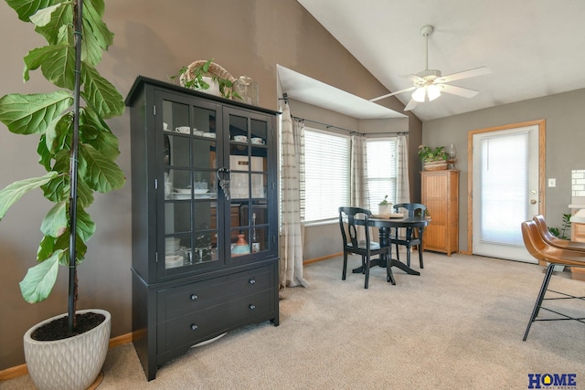 dining room featuring lofted ceiling, a ceiling fan, baseboards, and light carpet