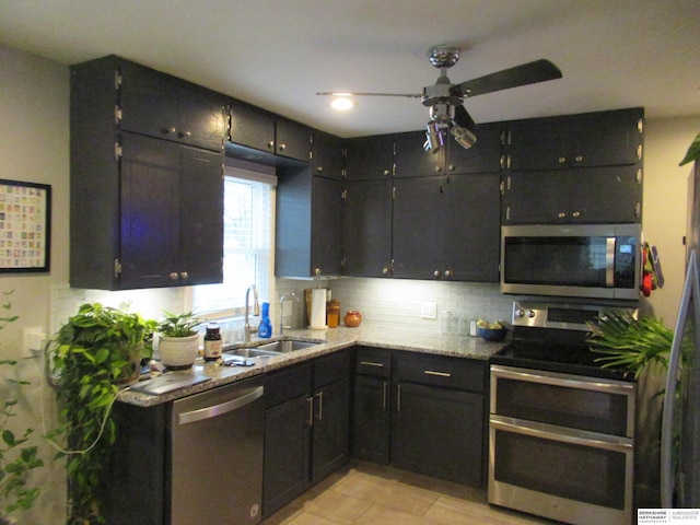 kitchen featuring a sink, light stone counters, backsplash, appliances with stainless steel finishes, and light tile patterned flooring