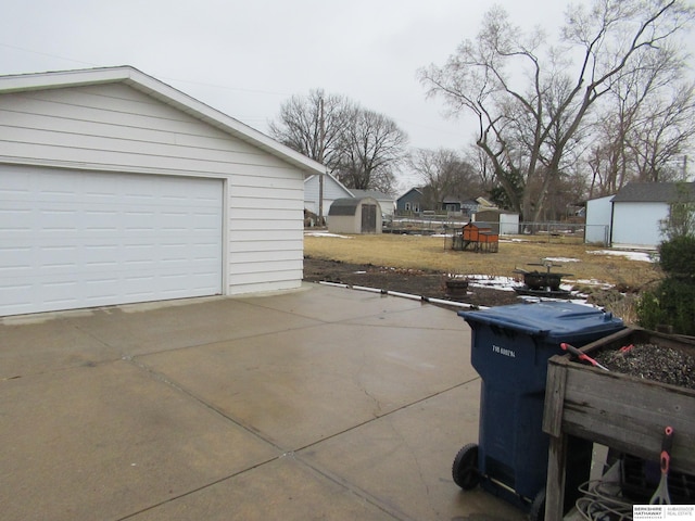 view of patio with a garage, an outdoor structure, and fence