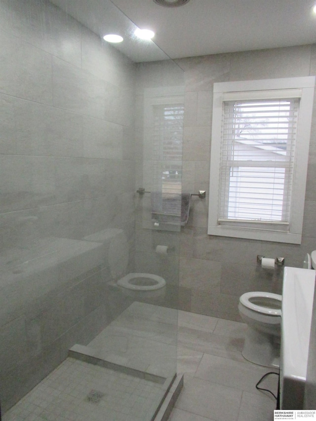 full bath featuring toilet, tile walls, and a tile shower