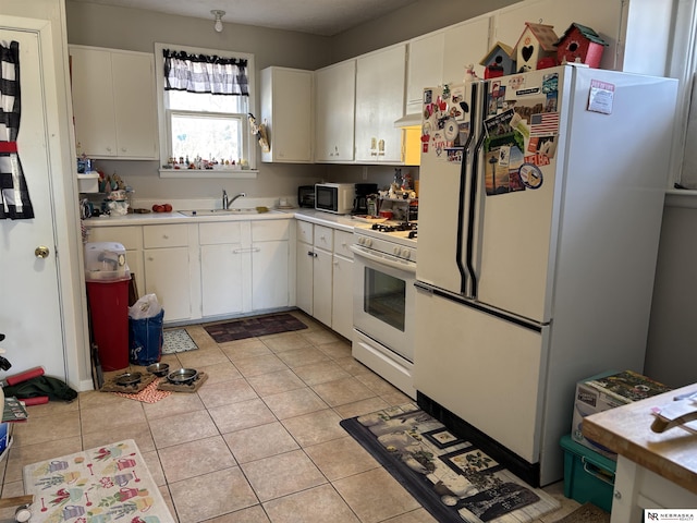 kitchen featuring a sink, white cabinetry, white appliances, light countertops, and light tile patterned floors