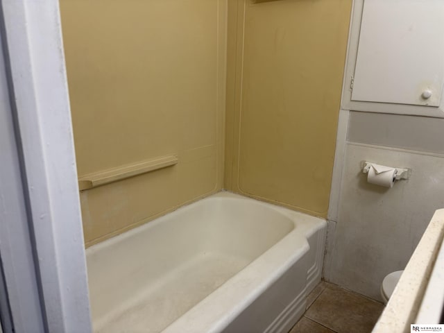 full bath with tile patterned flooring, toilet, and a tub